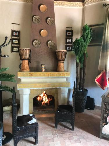 a living room with a fireplace and two chairs at Les Jardins de Ryad Bahia in Meknès