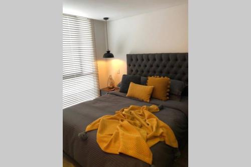 - une chambre avec un lit doté d'une couverture jaune dans l'établissement APARTAESTUDIO AMOBLADO,FURNISHED STUDIO APARTMENT WIFI gratuito, à Bogotá