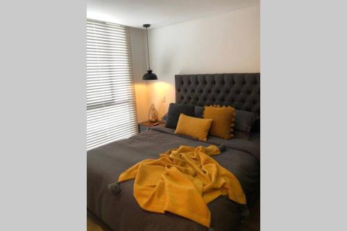 a bedroom with a bed with a yellow blanket on it at APARTAESTUDIO AMOBLADO,FURNISHED STUDIO APARTMENT WIFI gratuito in Bogotá