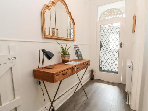 a room with a table with a lamp and a mirror at The Robins in Filey