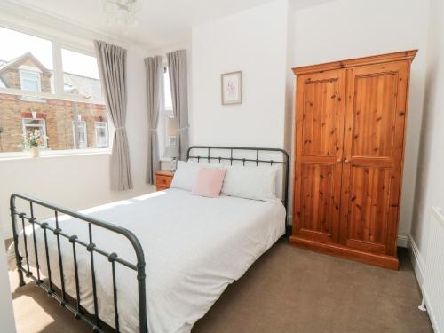 a bedroom with a bed and a wooden cabinet at The Robins in Filey