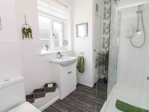 a white bathroom with a sink and a shower at Martingale in Torquay