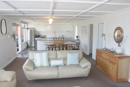 a living room with a couch and a kitchen at Elusive Penguin in Bicheno