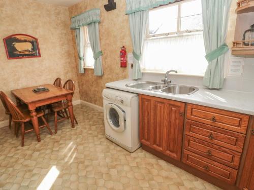 a kitchen with a sink and a washing machine at Honeysuckle in Wooler