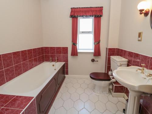 a bathroom with a tub and a toilet and a sink at Cherryburn Cottage in Wooler