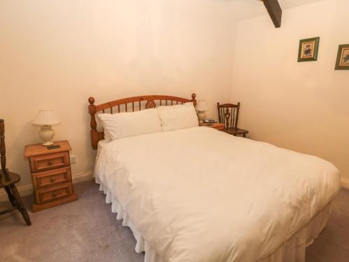 a bedroom with a large white bed and a night stand at The Smithy in Wooler