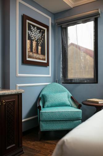 a blue room with a chair and a window at Romantique Hotel De Hanoi in Hanoi