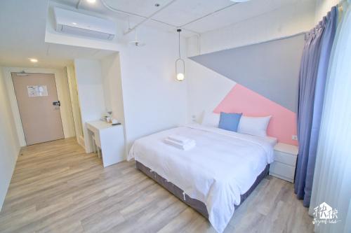 a bedroom with a white bed and a pink wall at Jezreel Inn in Kaohsiung