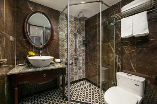 a bathroom with a toilet and a sink and a mirror at Romantique Hotel De Hanoi in Hanoi