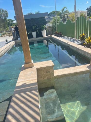 a swimming pool with blue water and a wooden pillar at Verdana Rental Residencial Arlene II SFM in San Francisco de Macorís