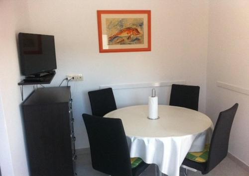 Cette chambre dispose d'une télévision et d'une table avec des chaises. dans l'établissement Apartment in Lopar with sea view, terrace, air conditioning, washing machine (4848-1), à Lopar