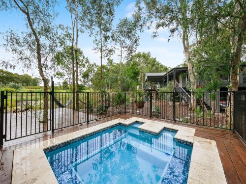 a swimming pool with a fence and trees at Fig Tree Luxury Guest House in Pokolbin