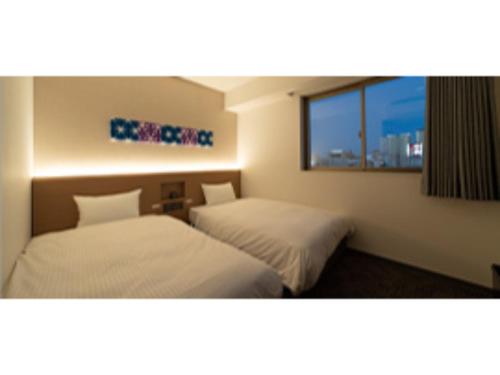 2 letti in una camera d'albergo con finestra di R&B Hotel Nagoya Ekimae - Vacation STAY 15188v a Nagoya