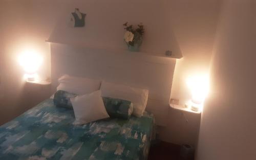 een slaapkamer met een bed met kussens en 2 verlichting bij La casina in Capoliveri