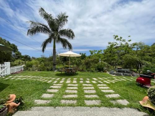 a patio with an umbrella and a table and a palm tree at Lanshan House in Donghe
