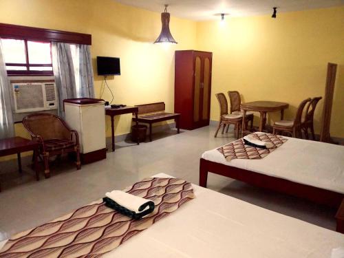 a bedroom with two beds and a table and chairs at Hotel Indsurya in Dibrugarh