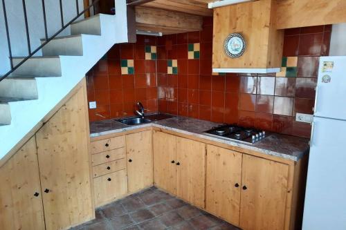 - une cuisine avec des placards en bois, un évier et un escalier dans l'établissement Cal fumat, à Capafons