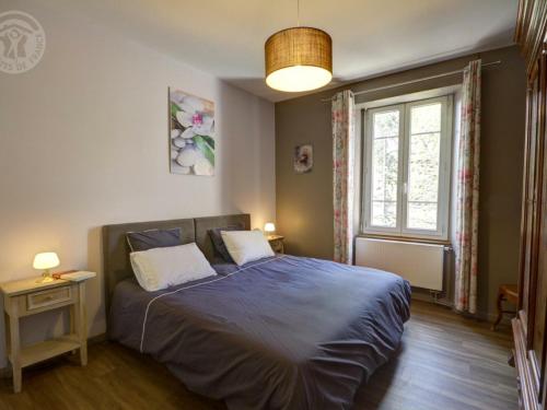 um quarto com uma cama com um cobertor azul e uma janela em Appartement Andrézieux-Bouthéon, 2 pièces, 2 personnes - FR-1-496-194 em Andrézieux-Bouthéon