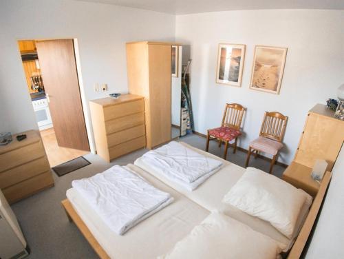 1 dormitorio con 1 cama blanca y 2 sillas en Sandkamp 4, Ferienwohnung 28 en Sankt Peter-Ording