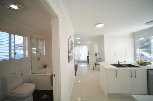 a white bathroom with a sink and a toilet at Craig's Place, 2br Short Term Accommodation - Western Sydney Area in Colyton