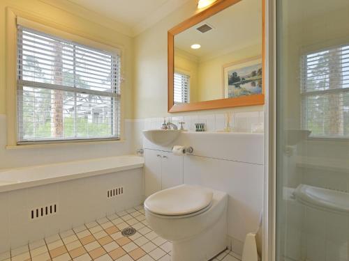 La salle de bains est pourvue de toilettes, d'un lavabo et d'un miroir. dans l'établissement Villa 2br Provence Villa located within Cypress Lakes Resort, à Pokolbin