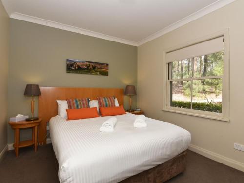 Un dormitorio con una cama grande con dos toallas encima. en Villa 2br Sangiovese Villa located within Cypress Lakes Resort, en Pokolbin