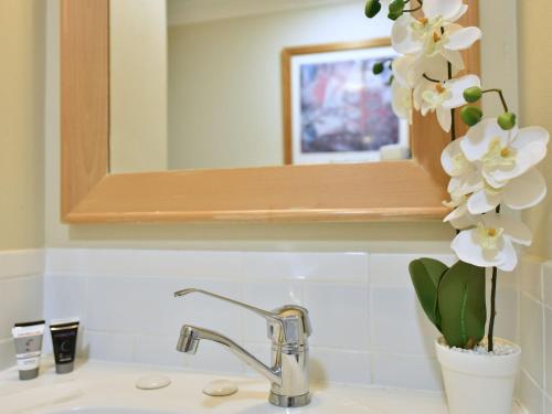 lavabo con espejo y jarrón de flores en Villa 2br Sangiovese Villa located within Cypress Lakes Resort, en Pokolbin