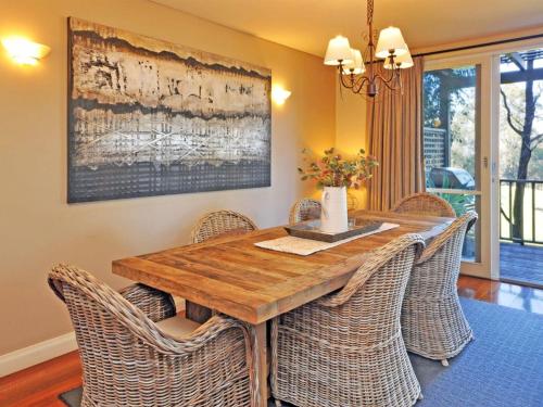 a dining room with a wooden table and wicker chairs at Villa 3br Beaujolais Villa located within Cypress Lakes Resort in Pokolbin