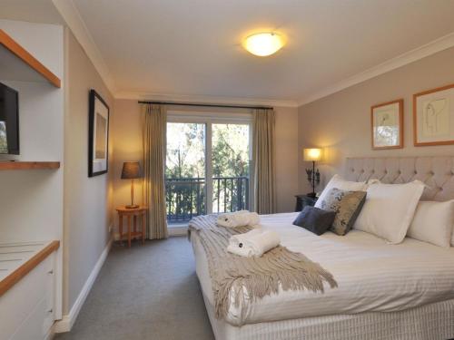 a bedroom with a large white bed with a window at Villa 3br Beaujolais Villa located within Cypress Lakes Resort in Pokolbin