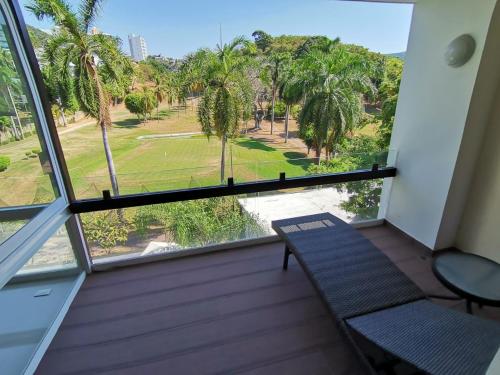 a balcony with two chairs and a view of a park at Suite Club Deportivo in Acapulco
