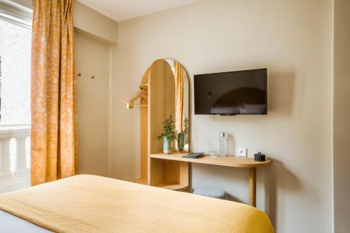 a bedroom with a bed and a desk and a tv at Hôtel AMI - Orso Hotels in Paris