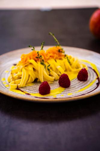 a plate of pasta with raspberries on a table at Bata Club Haus in Möhlin