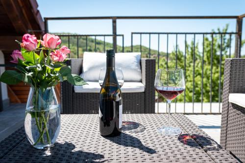 a bottle of wine and a vase of flowers on a table at Szigligeti Mandula Kert Vendégház in Szigliget