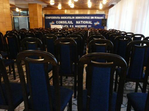 a group of chairs in a room with a sign at Hotel Traian Caciulata in Călimăneşti