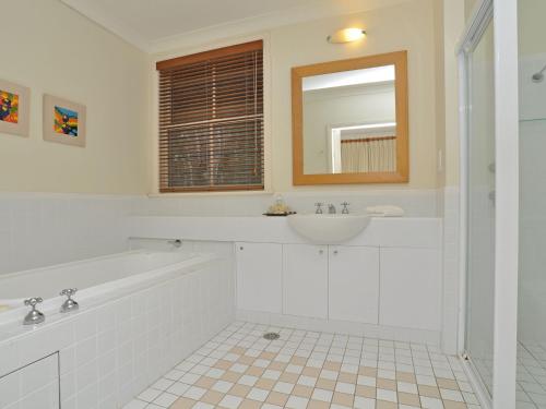 a bathroom with a tub and a sink and a mirror at Villa 1br Merlot Villa located within Cypress Lakes Resort in Pokolbin