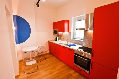 a red kitchen with red cabinets and a sink at ZACHÁR APARTMAN in Sopron