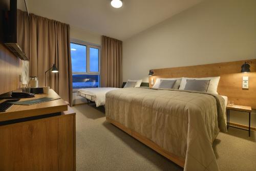 a hotel room with a large bed and a window at Hotel Element in Lipno nad Vltavou
