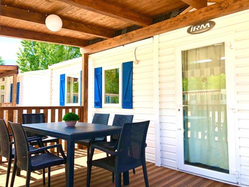 a patio with a table and chairs on a deck at Camping Village Nice Garden in Ardea