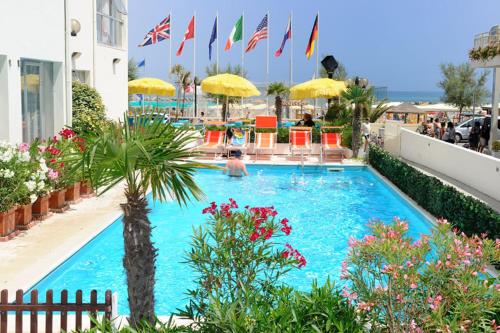 a swimming pool with a palm tree and umbrellas at Hotel International in Senigallia