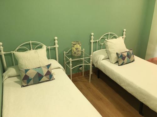 two twin beds in a room with green walls at Hostal Restaurante Alarico in Allariz
