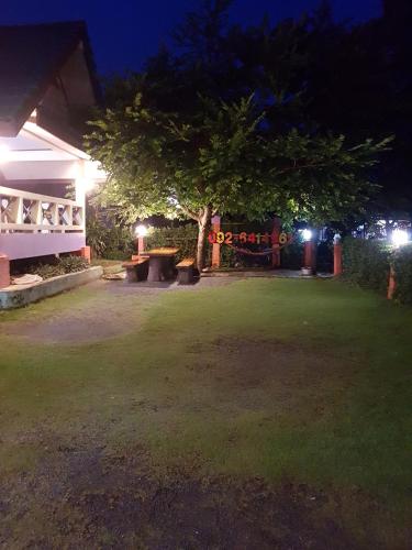 un parc de nuit avec un arbre et des bancs dans l'établissement บ้านสุขกมลแววดาวบ้านเดี่ยว1ห้องนอน, à Ban Pak Nam