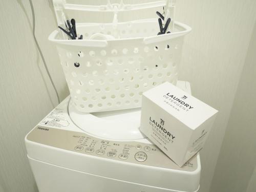 a laundry basket sitting on top of a washing machine at ケイアイコンホテルズ ふくしあ503 in Chikusachō