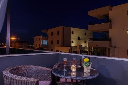 a table with two glasses of wine on a balcony at Vila White in Trogir