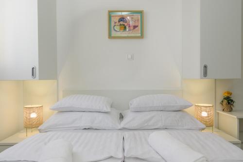 a white bed with white sheets and pillows at Vila White in Trogir
