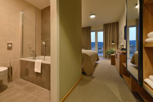a hotel room with a bathroom with a bed and a tub at Hotel Element in Lipno nad Vltavou