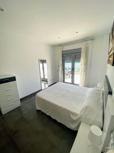 a white bedroom with a white bed and a window at APARTAMENTO JMHR 4 in Benajarafe
