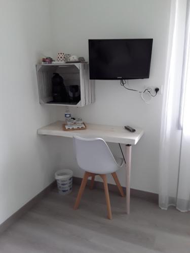 a computer desk with a monitor and a white chair at Chambre d'hôtes les Iris à Mios sur le Bassin d'Arcachon in Mios
