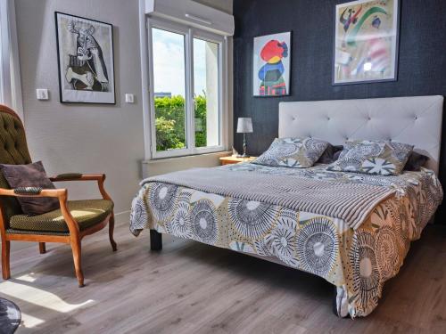 Un dormitorio con una cama y una silla y una ventana. en Les Roses, en Santec