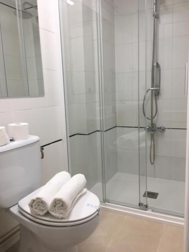 a bathroom with a shower and a toilet with towels at Hostal Restaurante Alarico in Allariz