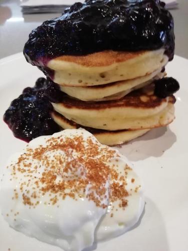 a stack of pancakes on a plate with blueberry sauce at Lakeside Country Guest House in Bassenthwaite Lake